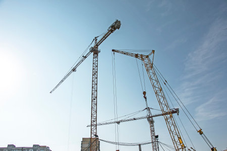 Construction crane against the blue sky. The real estate industry. A crane uses lifting equipment at...