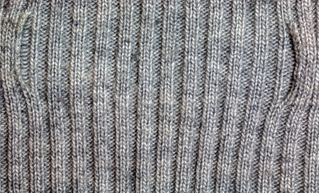 Gray knitted handmade sweater background. The texture of the surface of the woolen jersey made of...