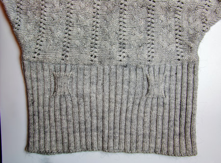 Gray knitted handmade sweater background. The texture of the surface of the woolen jersey made of yarn, close-up. Image for the background. Wool carpet or sweater. gray texture. modern design.の写真素材