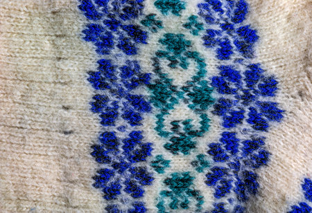 Background of white knitted fabric with blue-green handmade ornament from Argentine merino wool.の写真素材