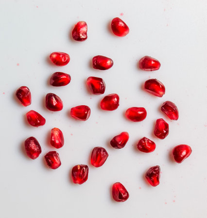 Ripe red pomegranate seeds on a white background.の写真素材