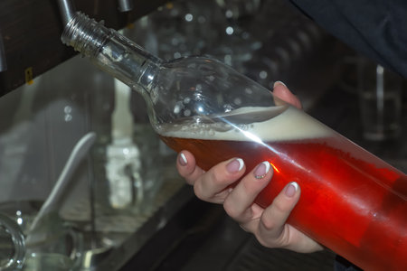 The hand of a bartender girl at a beer tap pours draft beer into a glass served in a restaurant or...