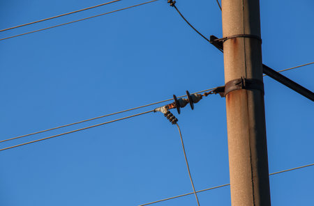 Electric pole with a linear wire against the blue sky close-up. Power electric field.の写真素材