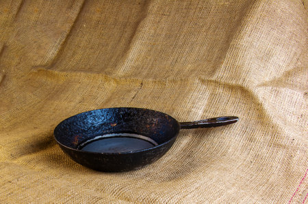 An old cast-iron skillet made in circa 1960 with burlap in the background.の写真素材