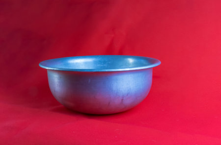 An old aluminum bowl made in circa 1960 against a red background.の写真素材