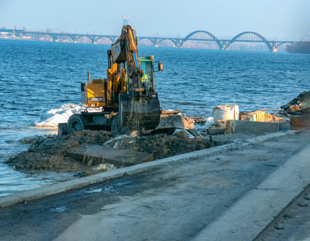 Dnepropetrovsk, Ukraine - 11.26.2021: Excavator works to strengthen the embankment. Hydraulic excavator working on the river bank.のeditorial素材