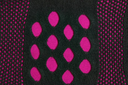 Black knitted mesh scarf on a burgundy fabric background. abstract background.の写真素材