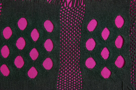 Black knitted mesh scarf on a burgundy fabric background. abstract background.の写真素材