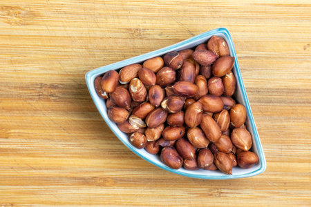 Roasted peanuts in a plate on a wooden kitchen board.