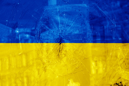 Bullet hole, cracks in the glass on a yellow-blue background. Ukraine flag on broken glass texture. Concept, Russian-Ukrainian war.の写真素材