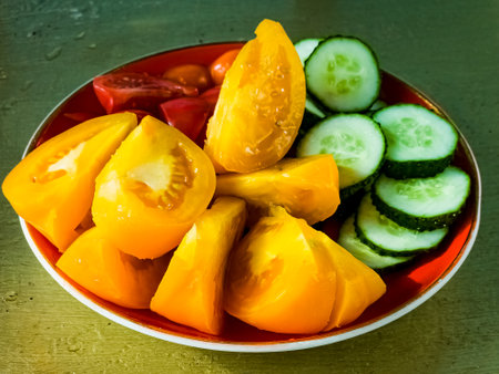 Close-up of slices of yellow and red tomatoes and cucumbers. Vegetables prepared for salad.の写真素材