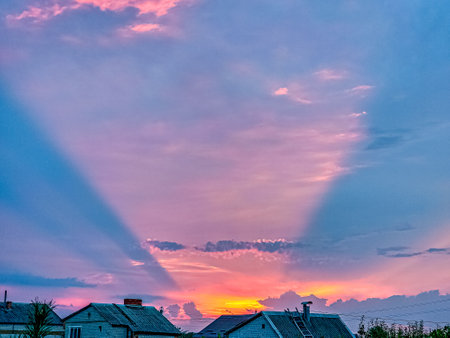 Unusual sunset. Pink conical optical effect from the rays of the setting sun in the clouds.の写真素材