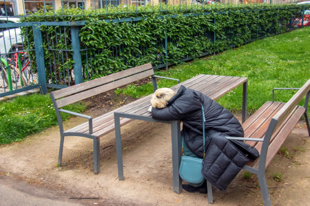 Vienna, Austria - 05.13.2023: Tired woman sleeps sitting at a table in one of the parks in Vienna.のeditorial素材
