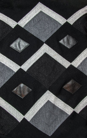 Detailed inserts in black genuine leather on a knitted woolen background with an abstract pattern. Abstract fabric texture.の写真素材