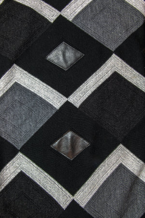 Detailed inserts in black genuine leather on a knitted woolen background with an abstract pattern. Abstract fabric texture.の写真素材