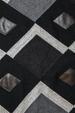Detailed inserts in black genuine leather on a knitted woolen background with an abstract pattern. Abstract fabric texture.の写真素材