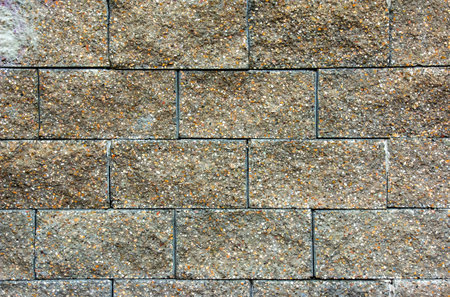 Cobble brown stone siding tile wall abstract background. House exterior with blocks tiled with cement. Crafted brickwork outer wall.の写真素材