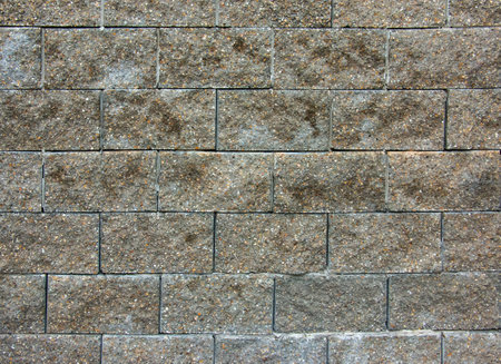 Cobble brown stone siding tile wall abstract background. House exterior with blocks tiled with cement. Crafted brickwork outer wall.の写真素材