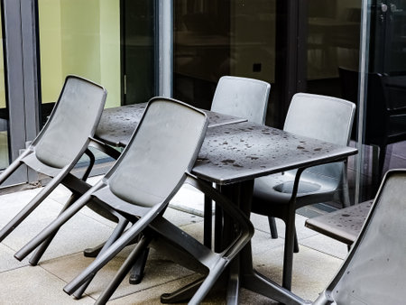 Table and chairs on an outdoor patio after the rain. There are no people in the cozy bar.