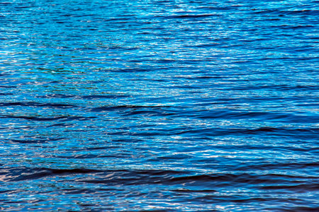 Water ripple texture background. Wavy water surface during sunset, golden light reflecting in the water.の写真素材
