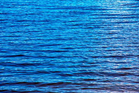 Water ripple texture background. Wavy water surface during sunset, golden light reflecting in the water.の写真素材