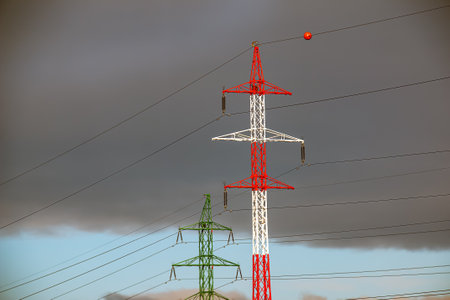 High voltage towers with electrical wires on dark cloudy sky background.の写真素材