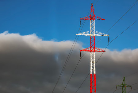 High voltage towers with electrical wires on dark cloudy sky background.の写真素材