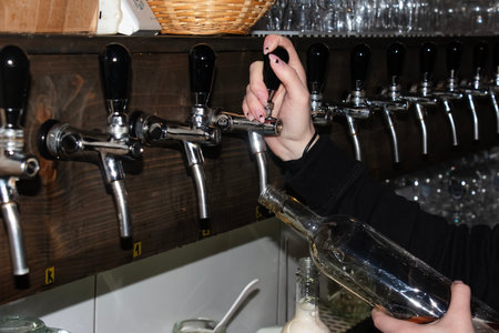 Behind the counter. Women's hands beautifully and easily pour beer into a bottle.の写真素材