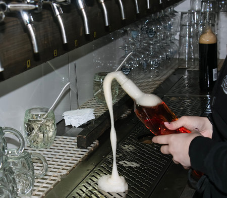 Behind the counter. Women's hands beautifully and easily pour beer into a bottle.の写真素材