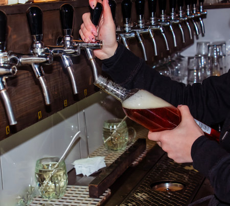 Behind the counter. Women's hands beautifully and easily pour beer into a bottle.の写真素材
