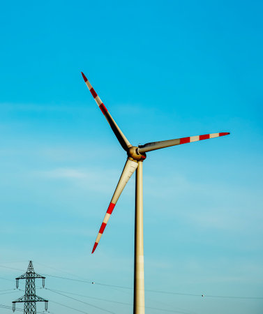 Wind farm park and high voltage towers next to a road in Austria in sunny weather.