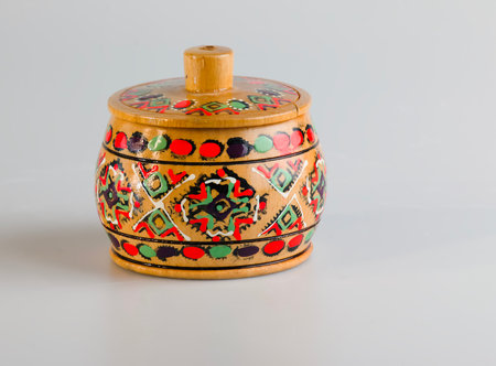 A wooden souvenir salt cellar with traditional Russian painting on a white background.