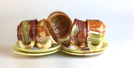 Empty cups made of multi-colored onyx in yellow-orange tones on a white background.の写真素材