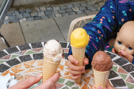 Three people holding ice cream cones with colorful toppings.