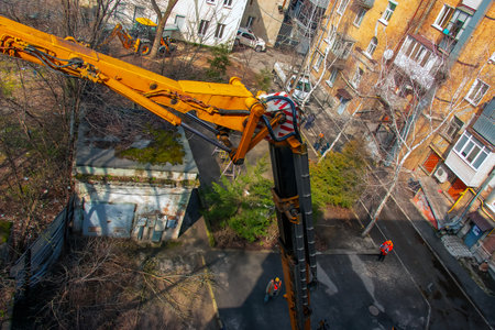 Municipal service workers stand with a chainsaw in a crane basket and trim dangerous trees.の写真素材