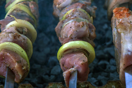 Cooking kebabs on a grill with smoke. Fresh brown BBQ meat cooked on an outdoor grill.の写真素材