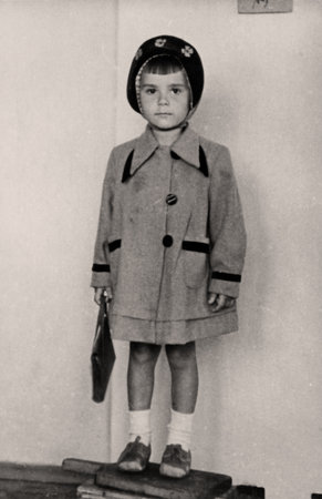 Vintage portrait of a charming little girl in a coat and hat. Chasov Yar, USSR. 1952