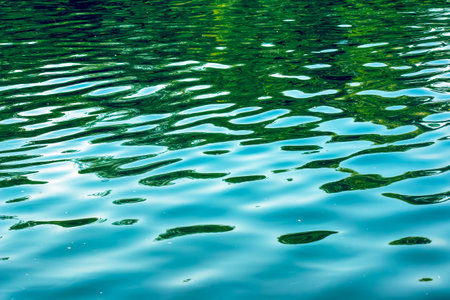 Water ripple texture background. Wavy water surface during sunset, golden light reflecting in the water.の写真素材
