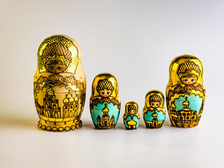 Five nesting dolls in a row of different sizes, Russian wooden dolls on a white background. Gold color with Orthodox housesの写真素材