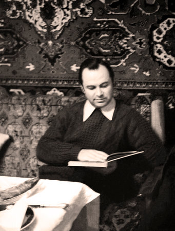 Vintage portrait of a man sitting on a sofa reading a book. Circa 1979.の写真素材