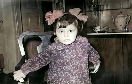 Vintage portrait of little girl with bows and velvet dress sitting in a chair. Retro photo from...