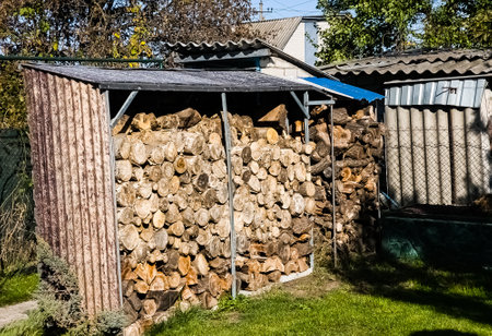 A neatly stacked pile of firewood under canopy. Preparing for autumn or winter.の写真素材