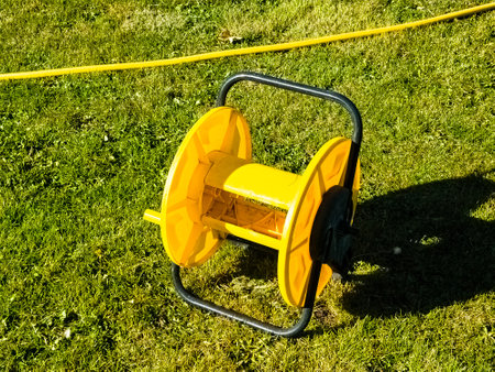Empty yellow hose reel on green grass. Proper storage of garden hoses.の写真素材