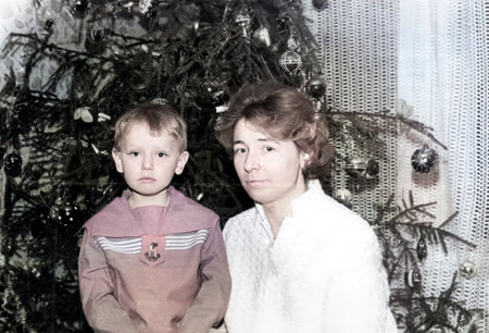 Vintage portrait of a little boy and his mother near a Christmas tree. Retro photo from 1970.の写真素材