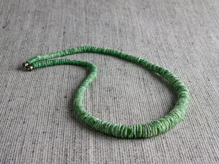Handmade polished green shell pieces necklace as a gift for a woman on a gray background. Natural jewelry. Summer jewelry.の写真素材