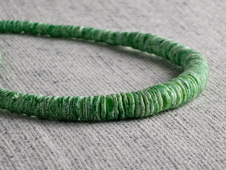 Handmade polished green shell pieces necklace as gift for a woman on a gray background. Natural jewelry. Summer jewelry.の写真素材