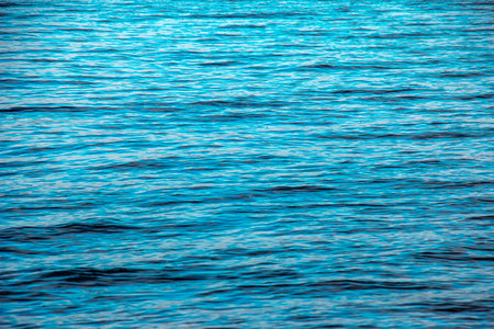 Water background of lake Traunsee in the Alps. The colorful texture of reflections of a clear...