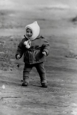 Vintage portrait of a cute little boy in white cap walking on the street in spring. Retro photo from 1967.の写真素材