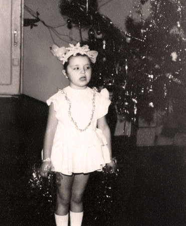 Vintage portrait of a girl dressed as a snowflake singing a song near a Christmas tree. Retro photo 1973.の写真素材