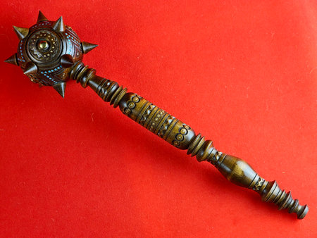 Ukrainian souvenir mace on a red background. Handmade on wood with the use of brass.